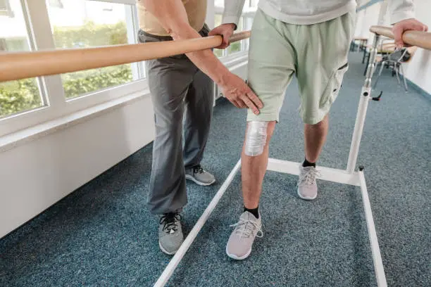 young man learning to walk again in rehabilitation on the bars